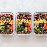 Three glass containers filled with rice, corn, olives, tomatoes, cucumbers, and lentils