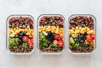 Three glass containers filled with rice, corn, olives, tomatoes, cucumbers, and lentils
